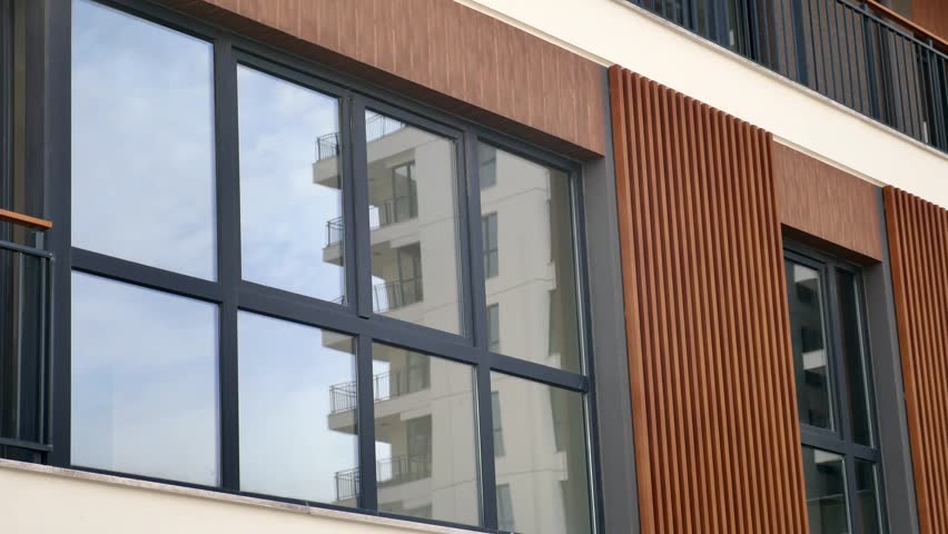 Modern apartment building exterior with large glass windows and stylish brown vertical wooden paneling details