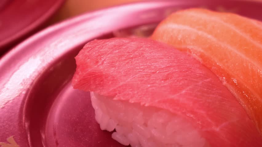 Fresh tuna and salmon nigiri sushi on red plate at Japanese restaurant
