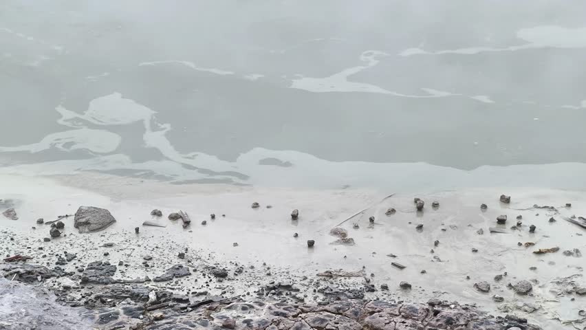 High angle view of Sikidang Crater Dieng with misty sulfur fumes and rocky terrain.