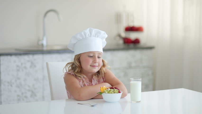 Girl sitting at table with fruit yogurt and glass of milk
