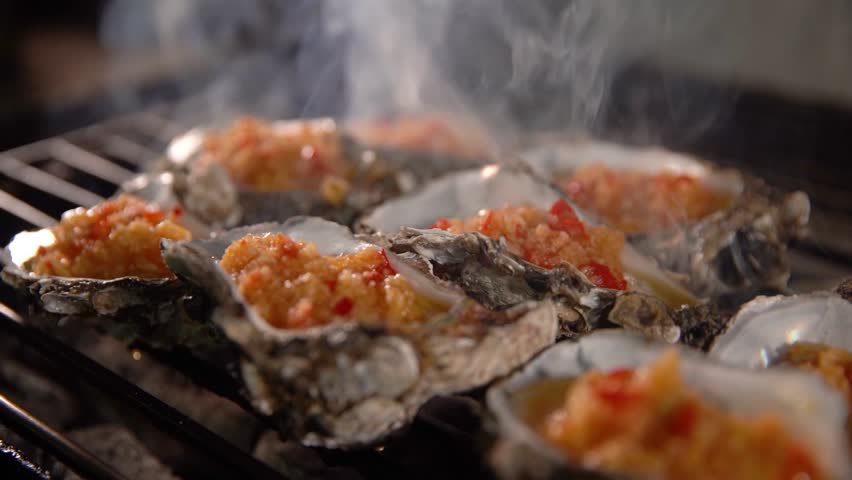 ilmed on January 6, 2024 in Guangzhou, Guangdong, China. Fresh oysters grilled over charcoal with garlic and scallions, a popular Cantonese street food snack.