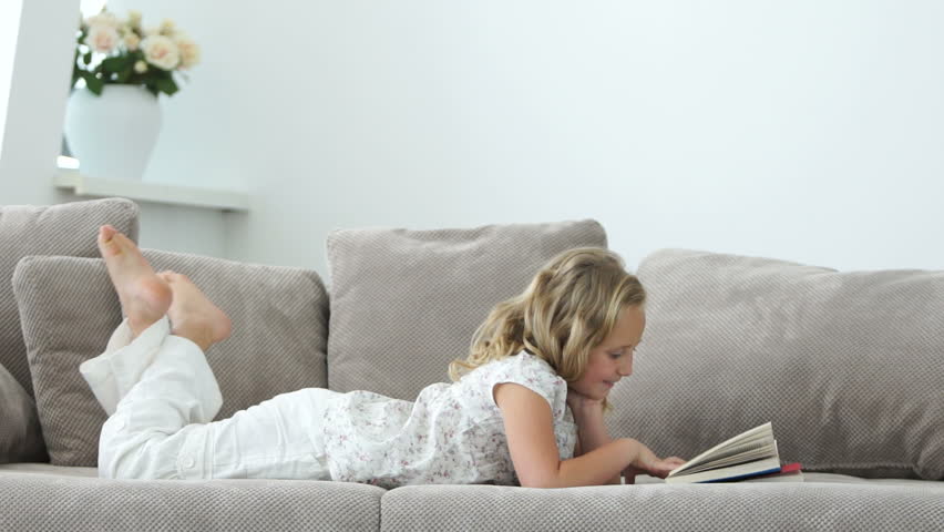 Girl lying on the sofa reading a book
