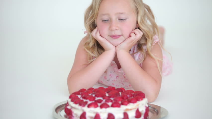 Little girl lying down and looking at the big cake
