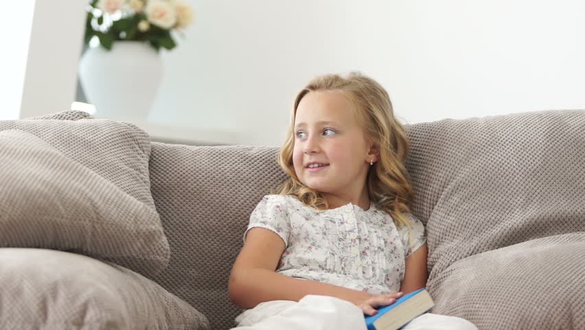 Girl reading a book on sofa and  smiling
