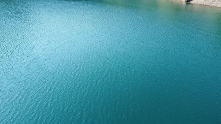 Clear blue lake surrounded by forested hills creating a peaceful natural landscape.