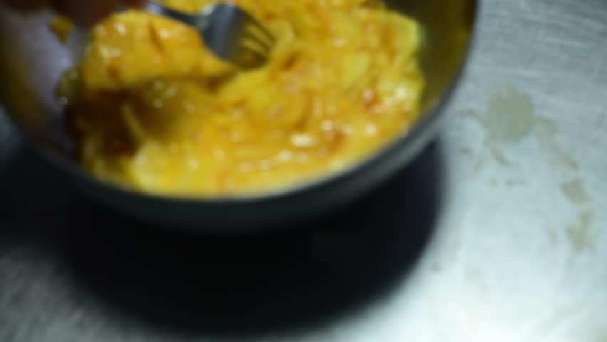 Chef whisking eggs and potatoes for a spanish omelette in a metal bowl