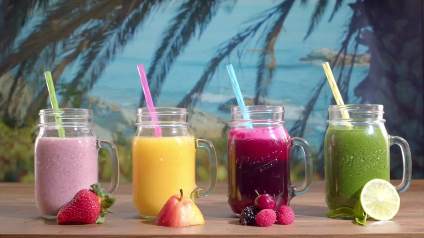 Colorful fruit drinks arranged on a beachfront table with tropical decorations. Fresh juices and smoothies create a vibrant summer mood, perfect for beach parties, travel destinations, and relaxing seaside moments.