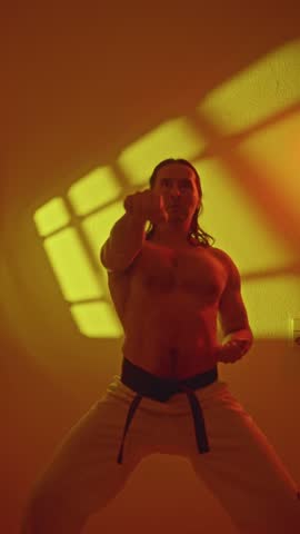 Fighter Under Lights. Man Executing Swift Punches In Yellow Illuminated Scene. Caucasian Male Practicing Quick Punching Moves With Energetic Intensity Under Warm Yellow Light. Speedy Karate Routine