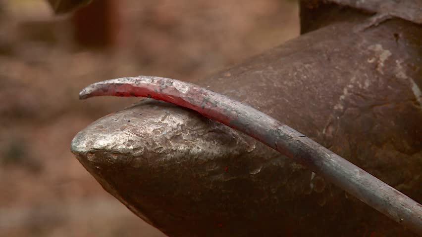 a blacksmith forges a metal product on an anvil