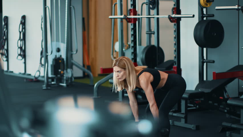 Strong Woman Lifting Weights in a Gym During Workout Session for Fitness
