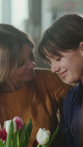 Intimate family scene with blooming tulips, Candid moment of mother and daughter sharing smiles and tender embraces