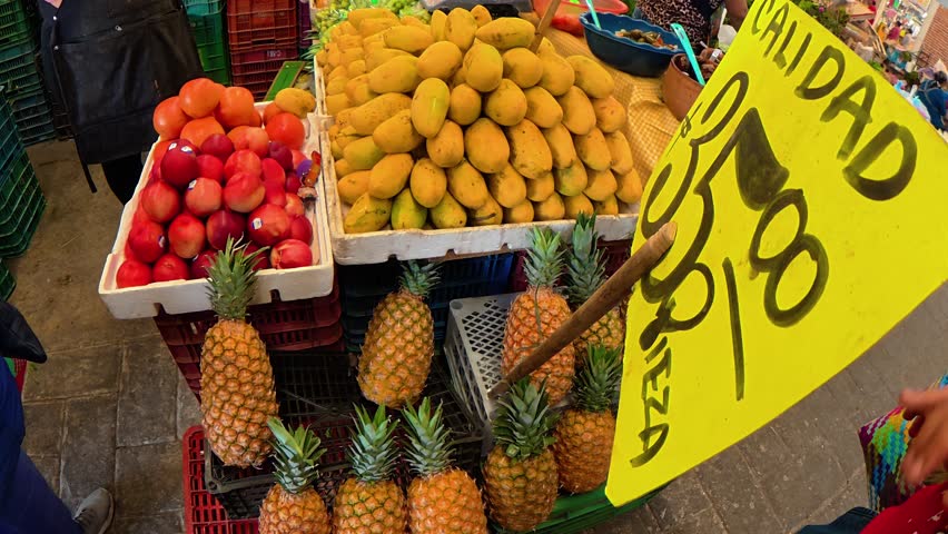 Colorful display of mangoes, pineapples, and plums for sale at a traditional market in mexico