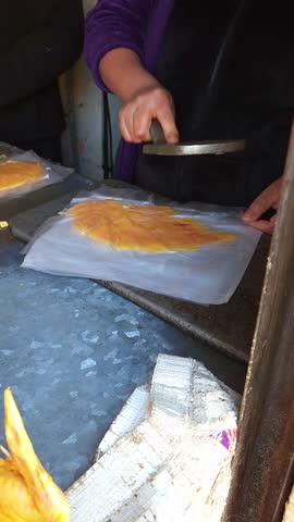 Woman flattening raw chicken breast with a metal press