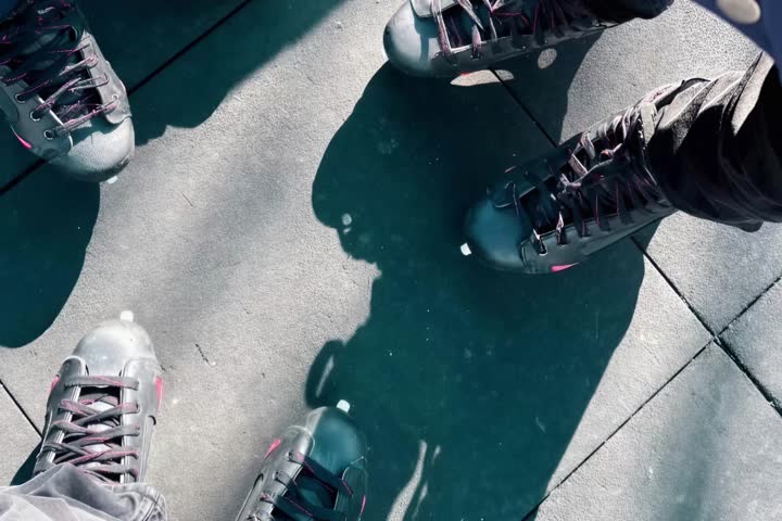 Seamless looping background of retro inline skates with slow zoom out and in. Top down view of friends in a circle on urban pavement. Y2K nostalgia youth culture concept.