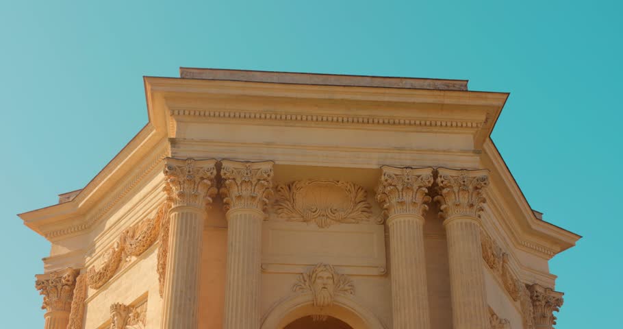 Peyrou Water Tower stands in Montpellier, France. The structure showcases classic architecture against a clear blue sky, with viewers appreciating its grandeur.