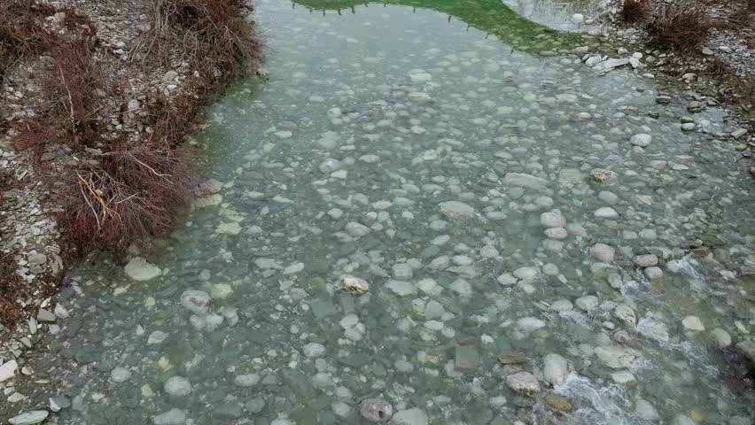 Person walking on Kalogeriko Plakidas stone bridge in Epirus Greece, establishing tilt up along reflection in water