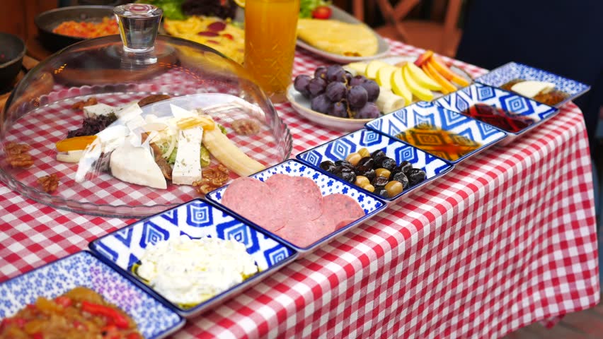 Turkish traditional breakfast table with various cheese olives and fresh orange juice on red checkered tablecloth