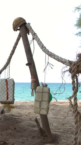 Close-up shot of styrofoam floats and ropes hanging from wooden posts on a beach