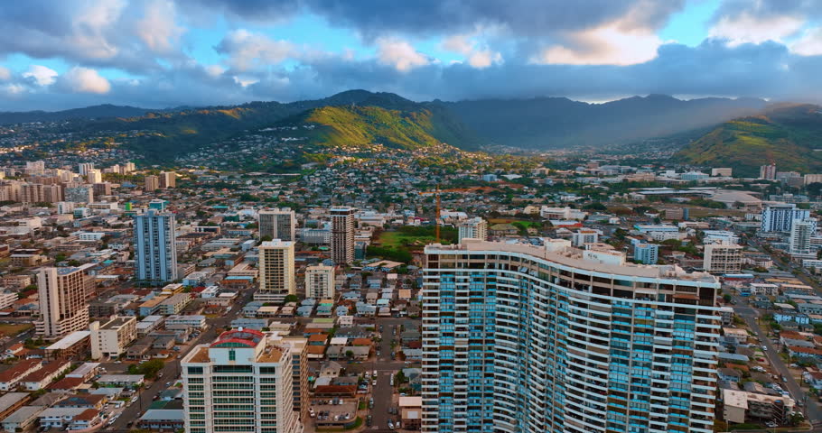 Urban landscape of beautiful Honolulu, Hawaii, USA. Green mountains around the city are under the clouds. Aerial view.