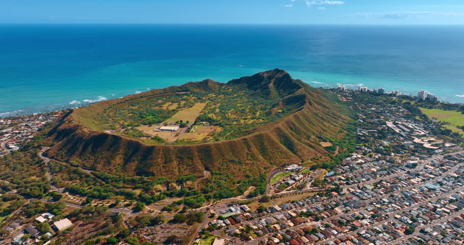 Multiple residential houses surround the beautiful Diamond Head Crater. Aerial perspective on the Hawaii landmark at the backdrop of the Pacific Ocean.