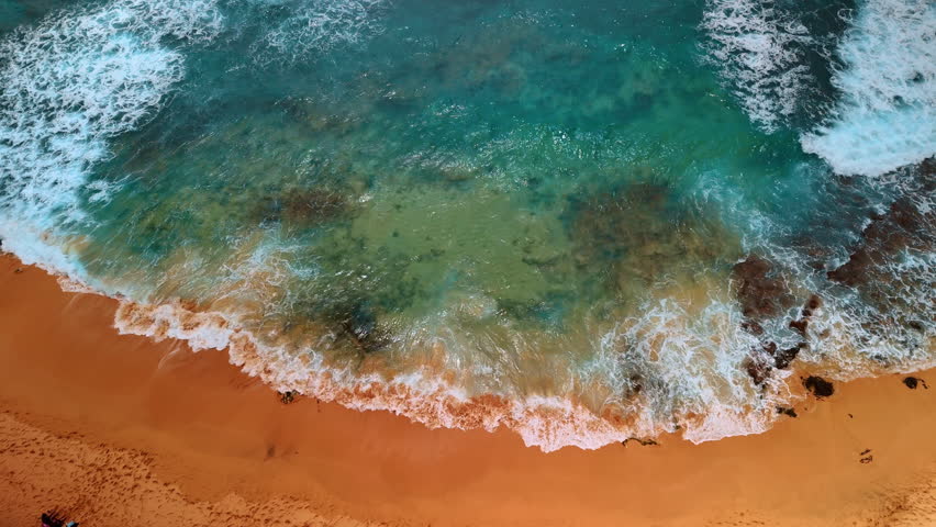 Beautiful clear water of the Pacific Ocean splashing on the shore. Yellow sandy beach of Hawaii, USA. Aerial view.
