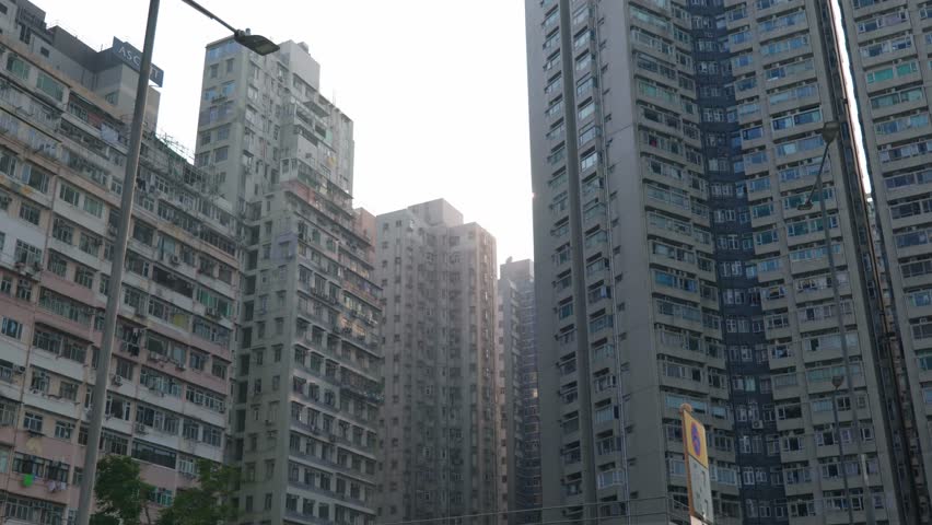 Panoramic view of apartment buildings and skyscrapers in downtown Hong Kong, China on a sunny day, showcasing dense urban living and modern architecture.