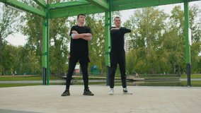 Two white men training under green pavilion, energetic synchronized squat repetitions, park lake backdrop, focused expressions, black activewear, sneakers, morning sunlight, determined camaraderie - Powered by Shutterstock - Get 15% off with code: PIKWIZARD15