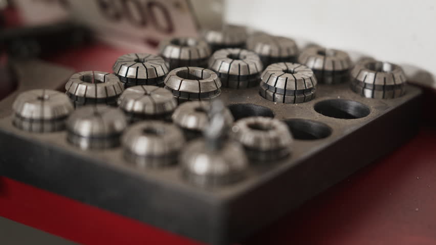 Close-up of a workshop tray filled with steel CNC machining collets, focusing on an end mill cutting tool