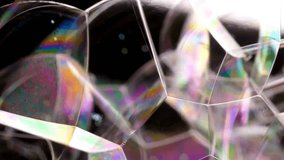 Extreme close-up captures numerous soap bubbles forming geometric shapes creating vibrant, rainbow colors across the bubble texture and unique pattern against black and white background. - Powered by Shutterstock - Get 15% off with code: PIKWIZARD15