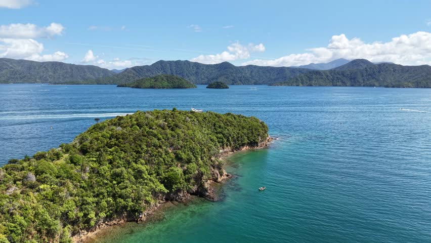 Flying low and descending towards water as powerboat appears from behind finger of land (Karaka Point, Queen Charlotte Sound, New Zealand)