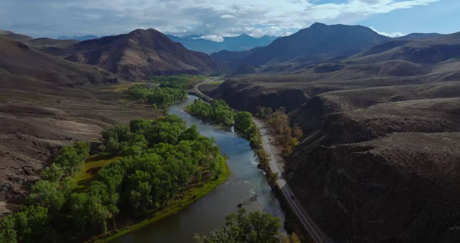 Highway 93 tracing river through wide Idaho valley under blue sky