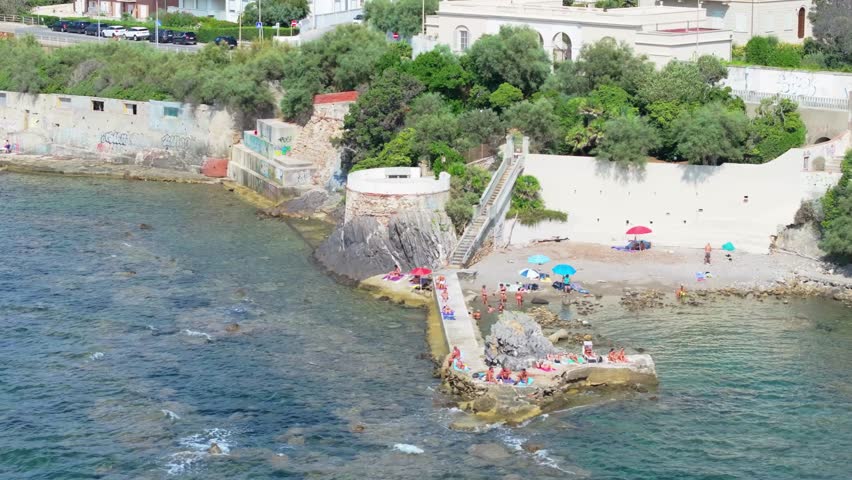 locals and tourists soaking up the summer sun on rocky shoreline of Tuscany, italy, city of Livorno
