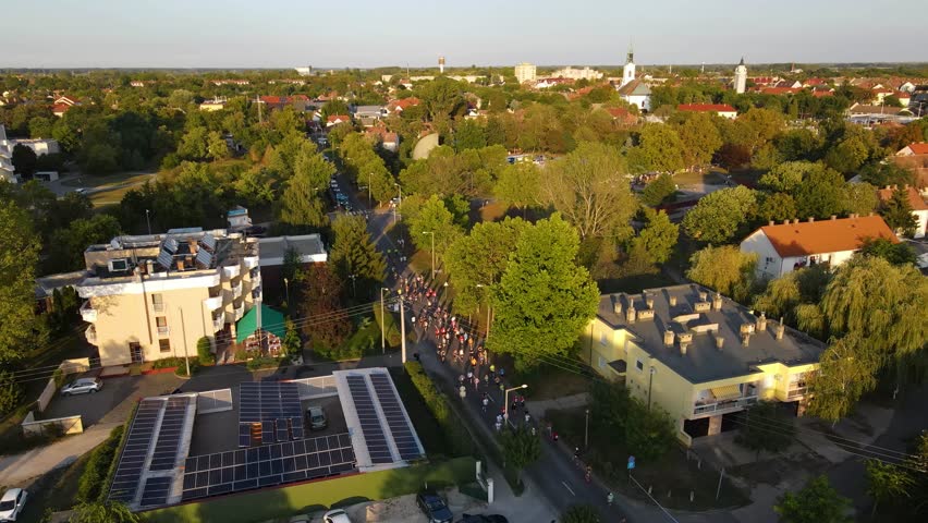 Running event participants competing in Kiskunhalas, Hungary street race, aerial view during golden hour
