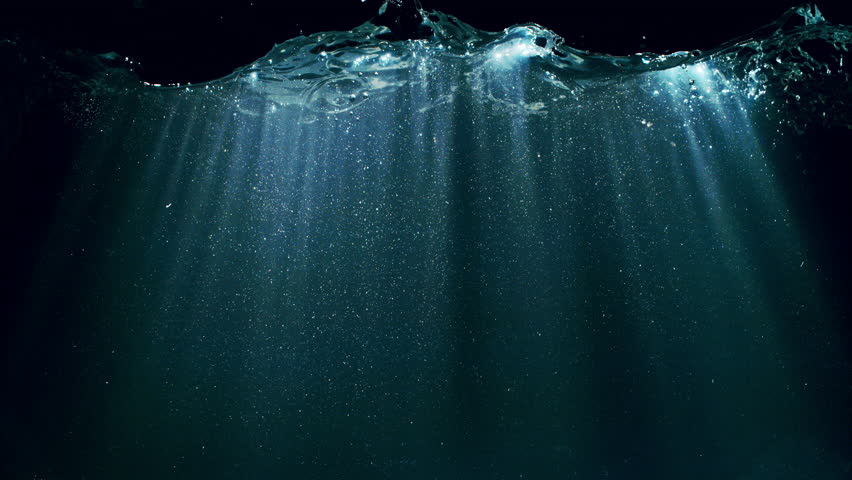 Dark Blue Ocean Surface Seen from Underwater , Super Slow Motion . Abstract Waves and Rays of Sunlight Shining Through