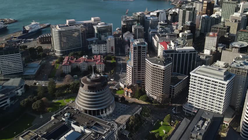 Aerial pull back from Parliament Building Beehive in Wellington, New Zealand, warm sunset.