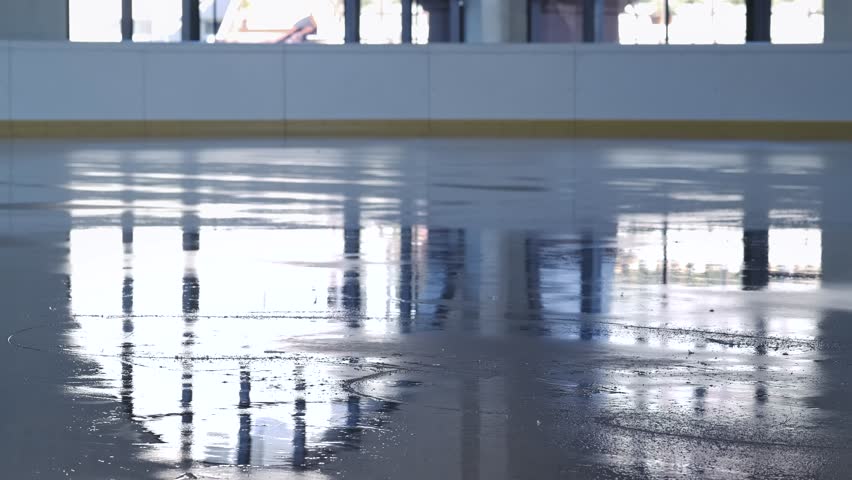 Close up of a figure skater legs gliding across a shiny indoor rink with reflections and shadows. An elegant winter sports scene demonstrating balance, movement, and training. Slow motion.