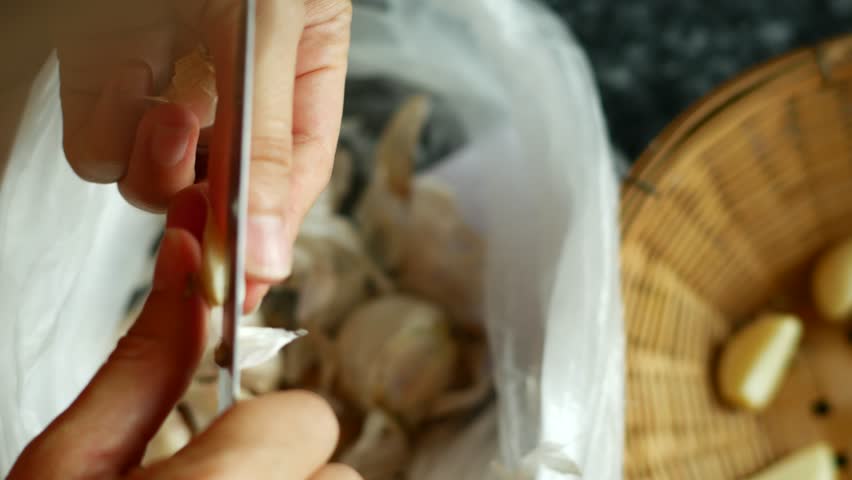 Woman Peeling Garlic with hands and knife