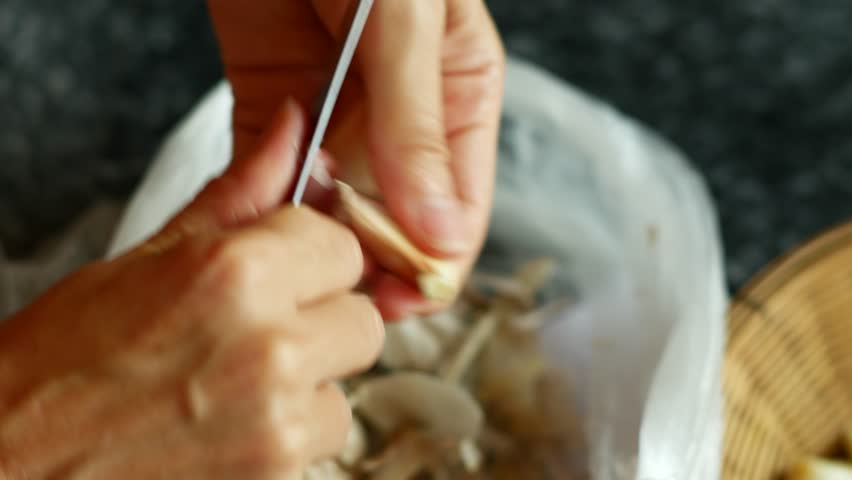 Woman Peeling Garlic with hands and knife