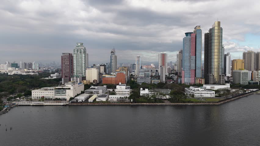 Stunning aerial panorama capturing the expansive manila city skyline, featuring modern high rise buildings and skyscrapers along the waterfront under a dramatic, cloudy sky in the philippines