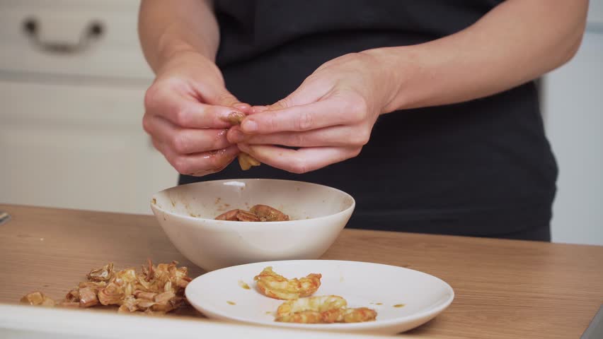 Peeling shrimp and placing meat on plate. Unrecognizable person removing shells from prawns. Cleaning fresh shrimp pieces for cooking. Preparing peeled shrimp for sushi roll filling