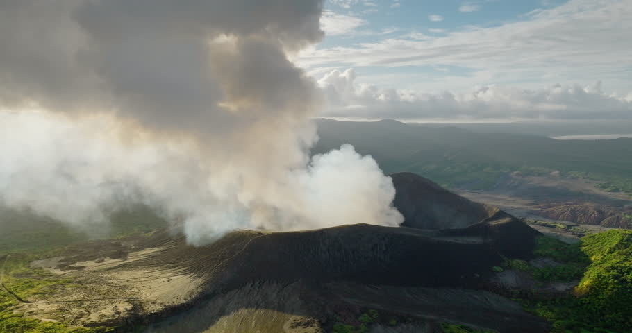Mount Yasur active volcano erupting, sending a large plume of ash and smoke into the air, revealing its raw power and the dramatic geological processes shaping Vanuatu Tanna Island. Aerial panorama