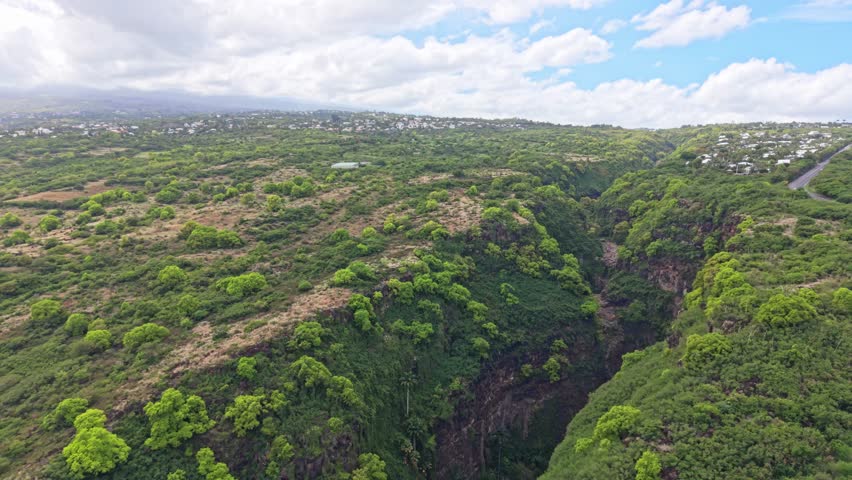 Forward drone flight along Ravine Bernica with slight right drift revealing deep green gorge and surrounding hills, Saint-Paul, Reunion Island