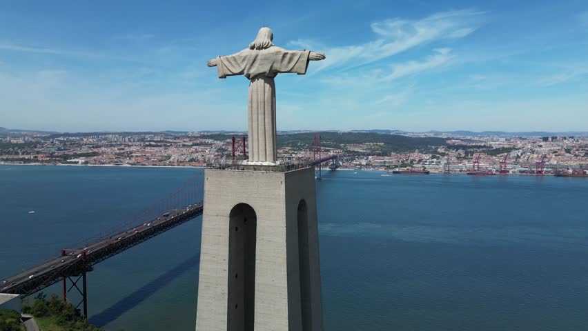 Drone footage capturing the iconic statue and the expansive river panorama with city visible in the distance.