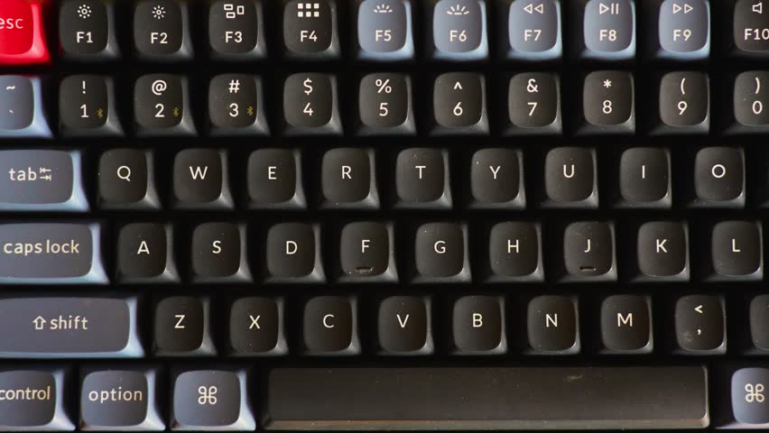 Close-up of Mechanical Keyboard with Red Enter Key. High-angle macro shot of a mechanical keyboard featuring black and grey keycaps with a distinctive red accent enter key