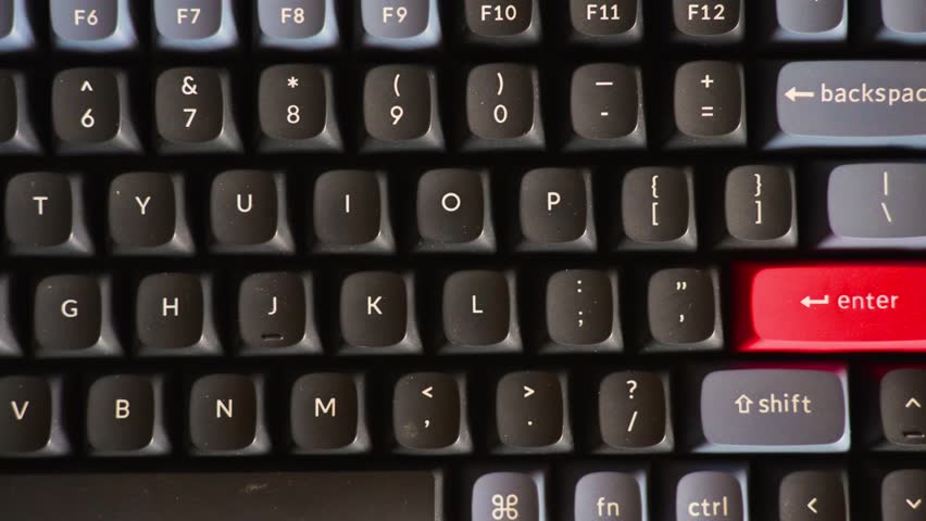 Close-up of Mechanical Keyboard with Red Enter Key. High-angle macro shot of a mechanical keyboard featuring black and grey keycaps with a distinctive red accent enter key