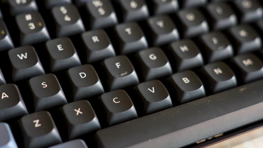 Close-up of Mechanical Keyboard with Red Enter Key. High-angle macro shot of a mechanical keyboard featuring black and grey keycaps with a distinctive red accent enter key