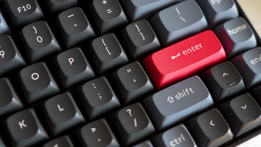 Close-up of Mechanical Keyboard with Red Enter Key. High-angle macro shot of a mechanical keyboard featuring black and grey keycaps with a distinctive red accent enter key