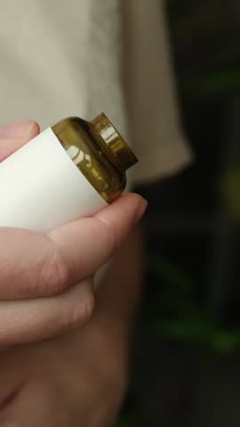 Vertical video. Meds, dietary supplements concept. Woman pouring pills into her hand. 