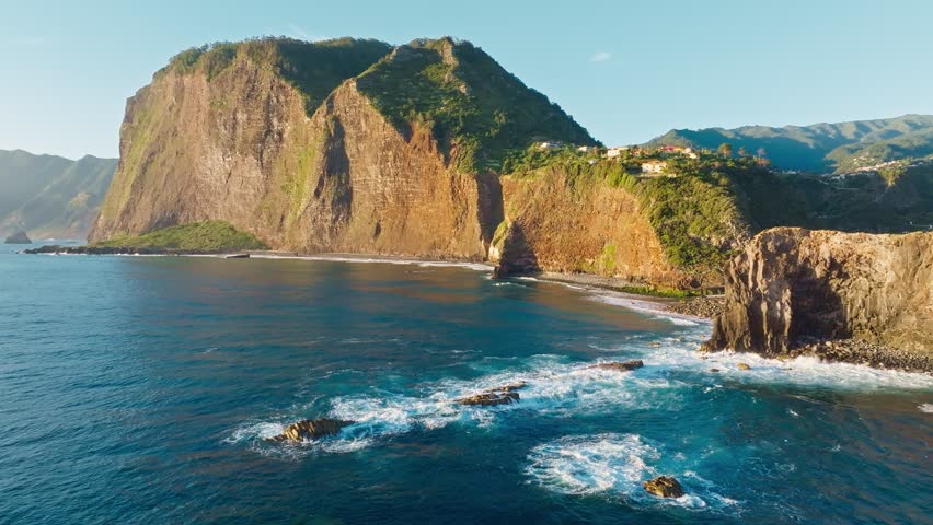 Aerial view of Madeira cliffs coastline landscape on sunrise, Guindaste viewpoint, Madeira island, Portugal. Pull away out retreat dolly shot