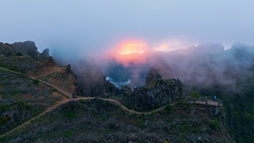 Mountains on sunset covered in fog and clouds with blooming Cytisus shrubs. Near Pico de Arieiro , Madeira island, Portugal. Push in approach dolly move